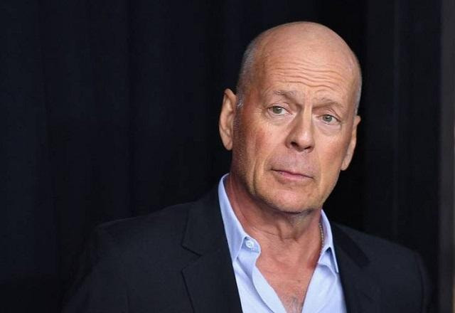 Bruce Willis usa roupa social e faz cara séria