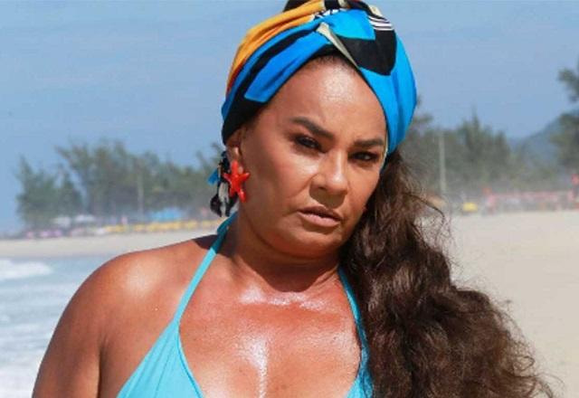 Solange Couto posa na praia usando biquíni azul e com lenço na cabeça