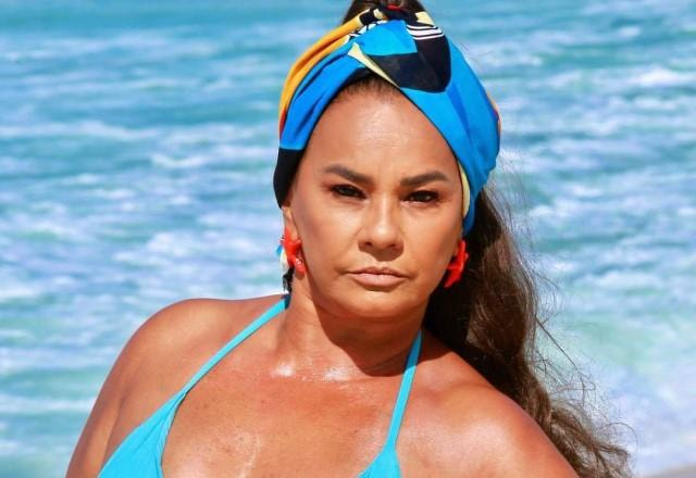 Solange Couto posa na praia usando biquíni azul e com lenço na cabeça