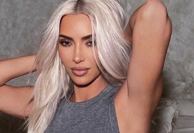 Kim Kardashian posa para foto em cima da cama.