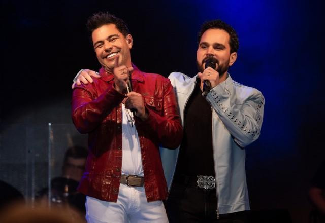 Zezé Di Camargo e Luciano posam juntos sorrindo no palco