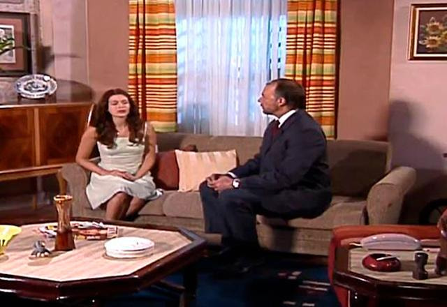 esmeralda e rodolfo sentados no sofá em uma sala de estar