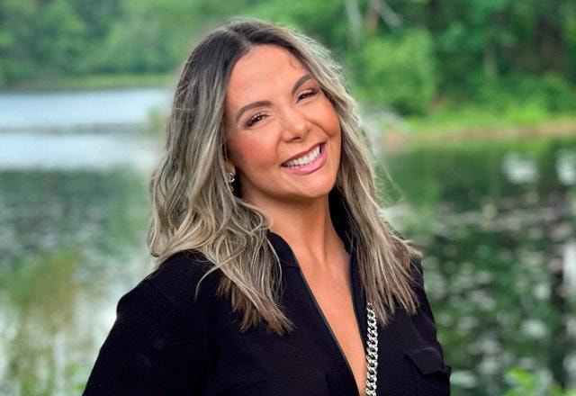 Carla Perez posa sorridente em frente a um lago