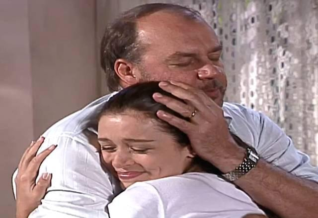 Esmeralda e Rodolfo se abraçando, ela sorrindo e ele com os olhos fechados e emocionados