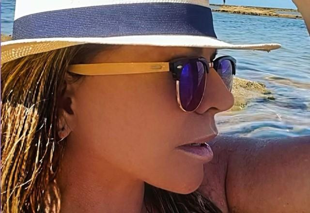 Christina Rocha tira selfie usando chapéu e óculos de sol no mar