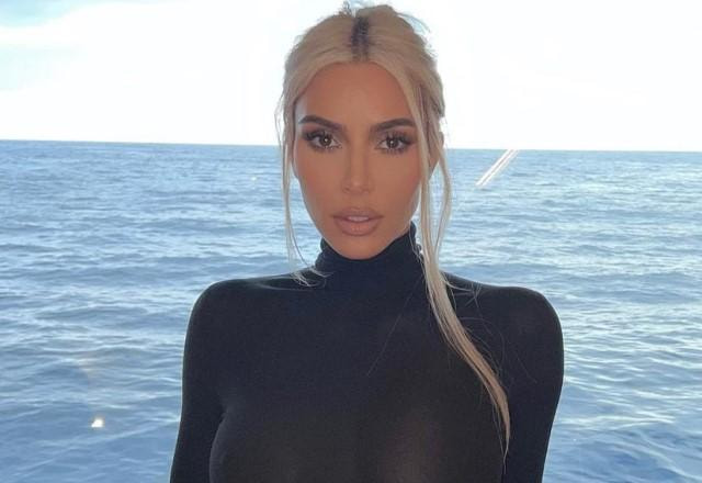 Kim Kardashian posa usando uma roupa toda preta em frente ao mar