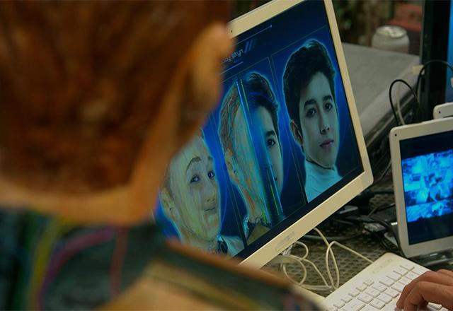 uma pessoa de costas olhando uma tela de computador com três fotos