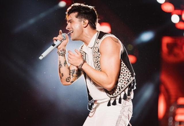 Luan Santana de lado e cantando durante show