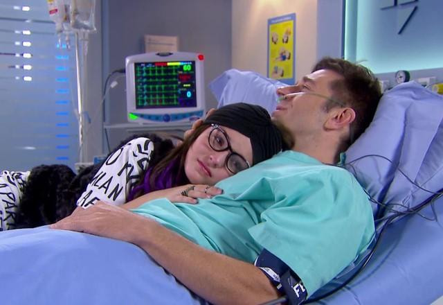 Isabela apoiada em Orlando, que está deitado na cama e