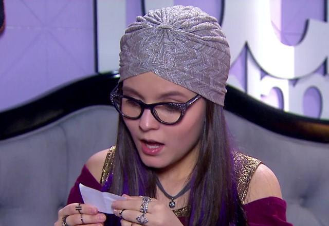 Manuela com expressão de assustada e segurando um papel na mão