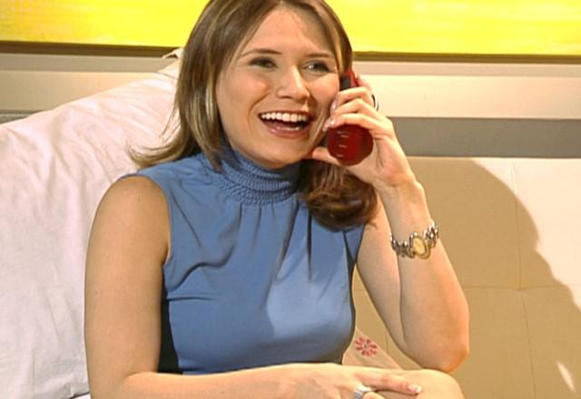 Débora falando ao telefone e sorrindo bastante