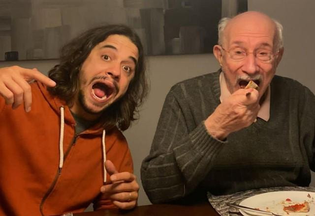 Guilherme Boury e Reynaldo Boury jantando pizza em uma mesa