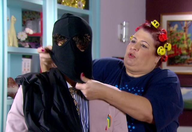 Meire colocando uma toca preta de assaltante em Dinho
