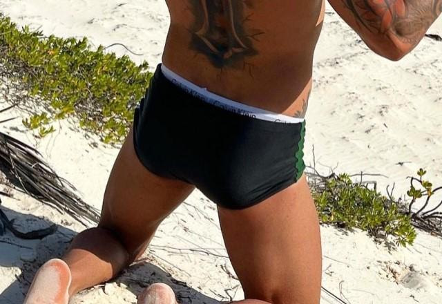 Gusttavo Lima posa ajoelhado na praia e usando sunga e cueca