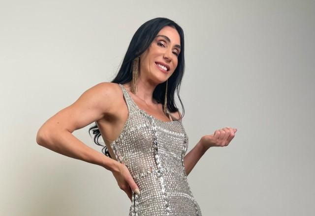Michelle Barros posa sorrindo e usando vestido prateado