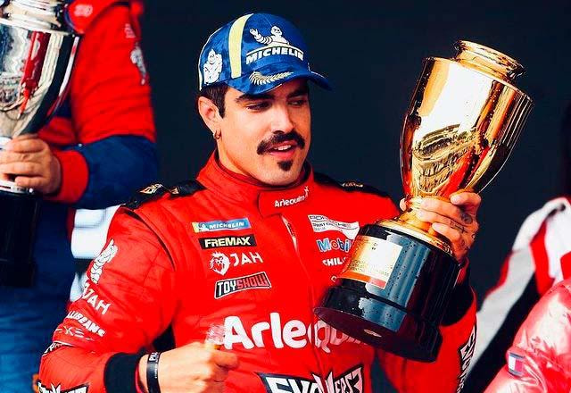 Caio Castro no pódio de uma corrida de automobilismo, com troféu na mão
