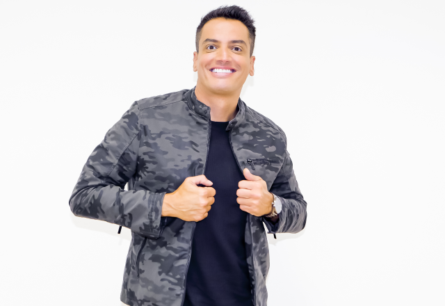 Leo Dias posa sorrindo e com os braços cruzados