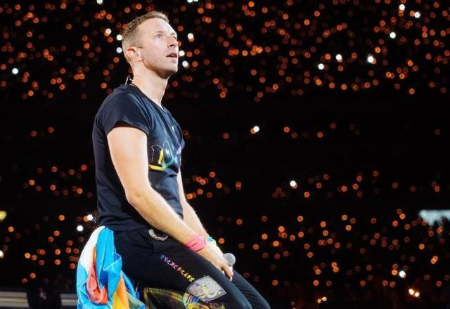 Chris Martin ajoelhado no palco durante show do Coldplay