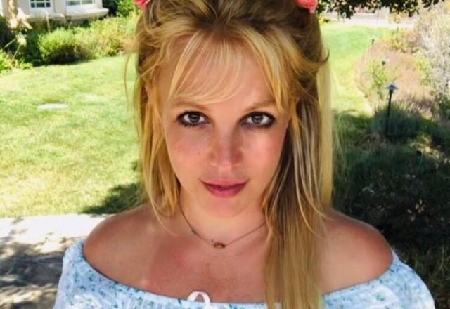 Britney Spears posa no jardim com uma camisa branca