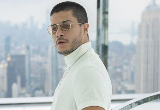 Arthur Aguiar tira foto olhando de lado, usando camisa branca e no topo de prédio
