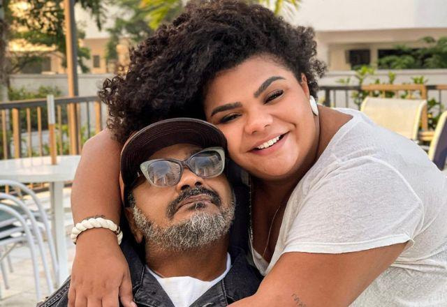 Arlindo Cruz e a filha, Flor Cruz, posam abraçados e sorrindo para a câmera