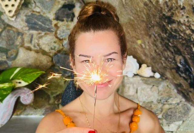 Fernanda Souza posa sorrindo e segurando uma vela de aniversário