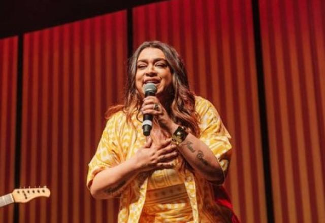 Preta Gil em cima do palco sorrindo e cantando