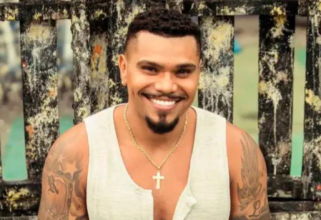 O cantor Naldo posa sorrindo e usando regata branca