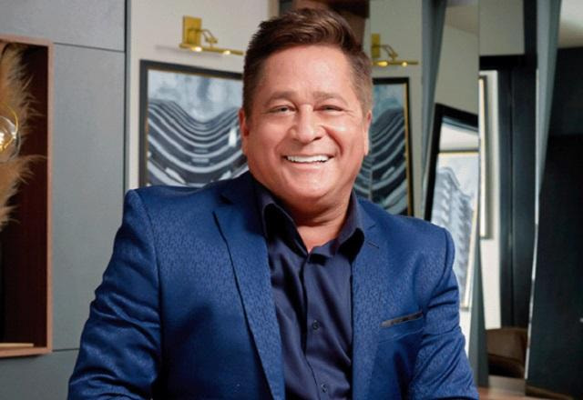 Leonardo posa sorrindo e usando um terno azul escuro