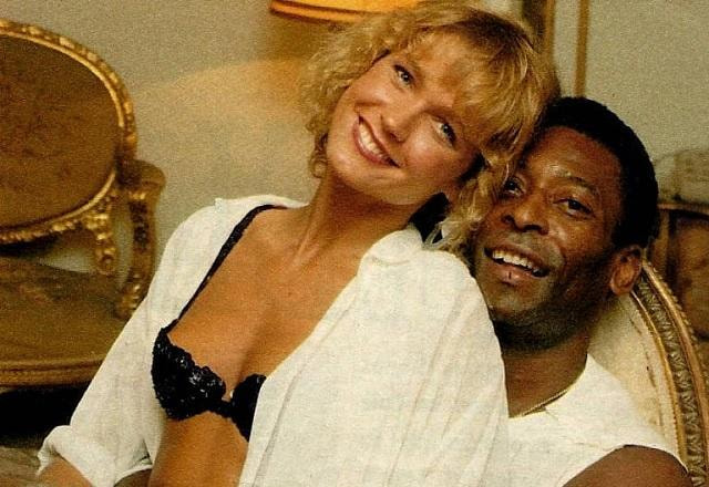 Xuxa posa sentada no colo de Pelé e os dois sorriem para a foto