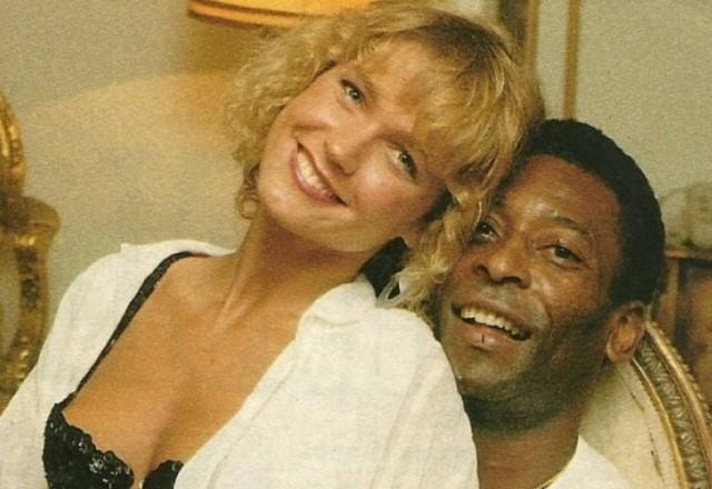 Xuxa posa sentada no colo de Pelé e os dois sorriem para a foto