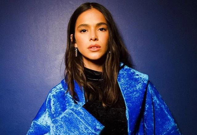 Bruna Marquezine posa olhando fixo para a frente, usando um look azul