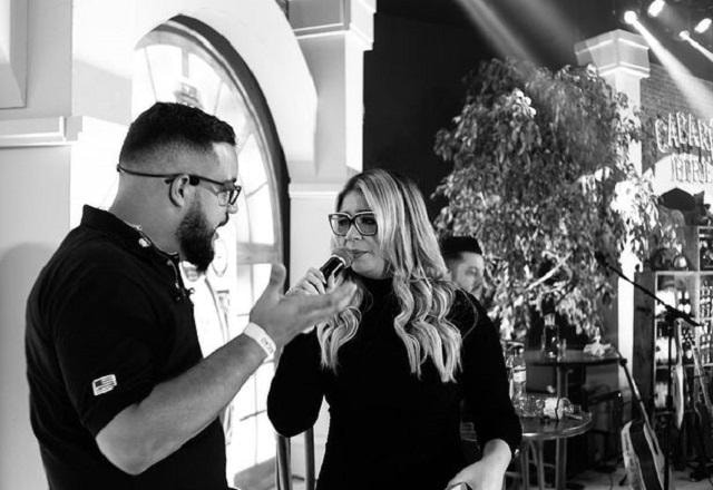 Henrique Bahia e Marília Mendonça em foto preto e branco, durante um show da cantora