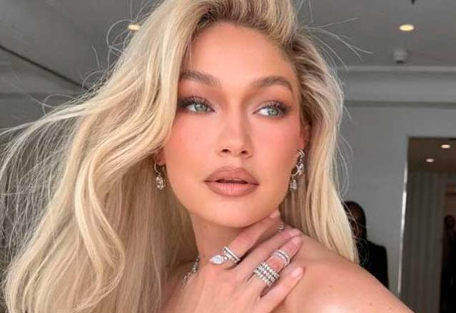 gigi hadid posa olhando de lado e com a mão no pescoço