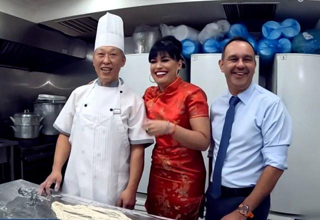 Milene Pavorô em uma cozinha ao lado de um chef e um garçom