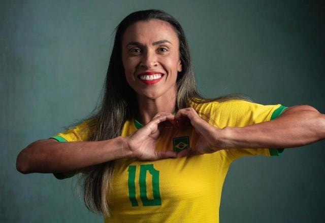 Marta posa sorrindo e fazendo um coração com as mãos