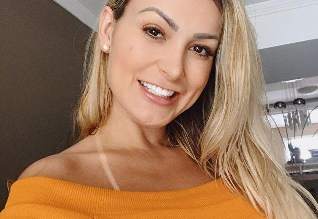 Andressa Urach tira selfie sorrindo e usando blusa laranja