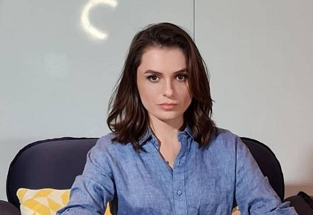 Monica Iozzi posa sentada e olhando para a frente séria