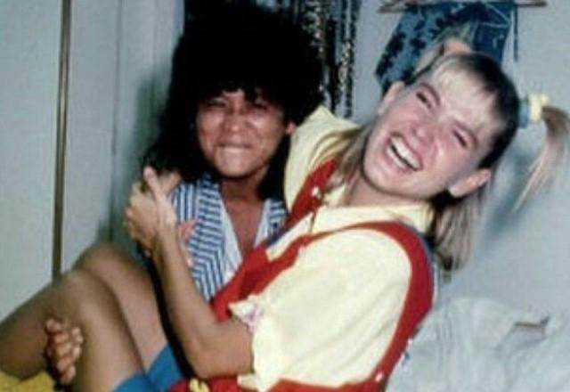 Marlene Mattos carrega Xuxa no colo e as duas sorriem para foto