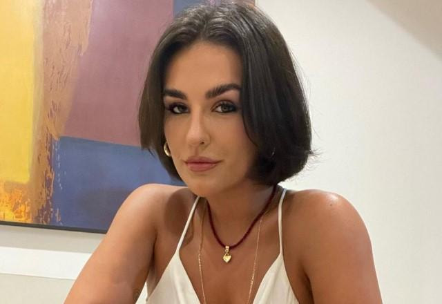 Kéfera posa sentada em sofá e usando blusa branca