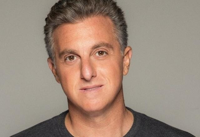 Luciano Huck posa em frente a um fundo cinza