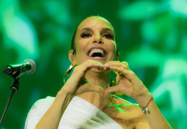 Ivete Sangalo sorri em cima do palco e faz coração com as mãos