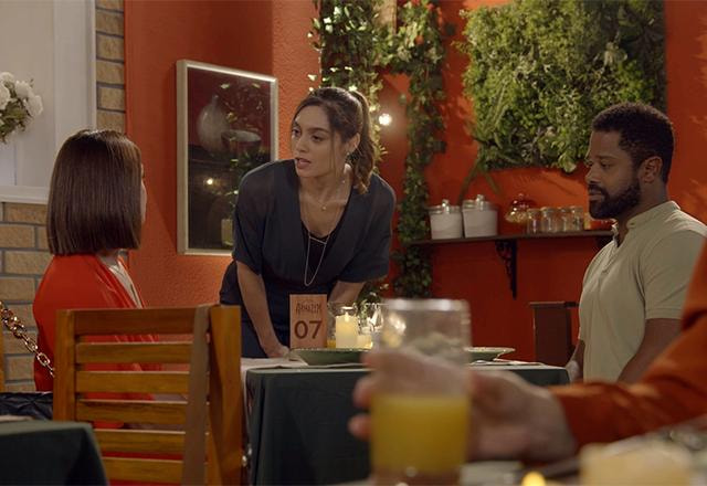 Vera, Mariana e Bernardo conversando em uma mesa de restaurante