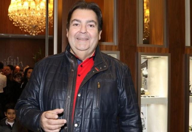 Faustão sorri para a câmera com uma blusa de couro preta