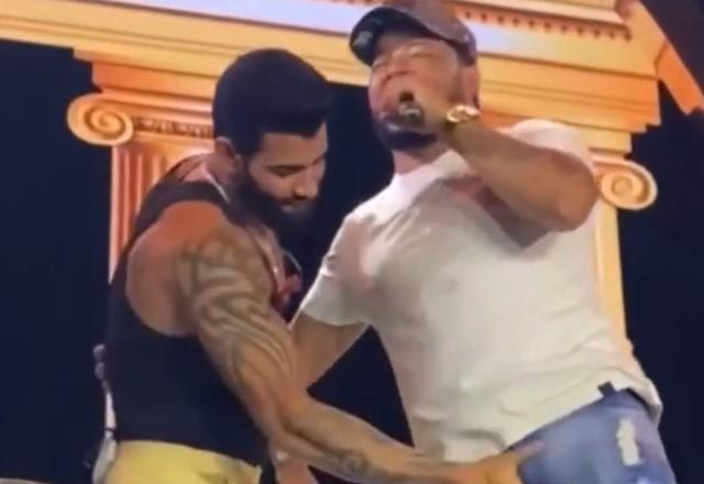 Gusttavo Lima no palco segurando parte íntima de cantor