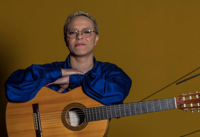 Maria Gadú com os braços apoiados no violão