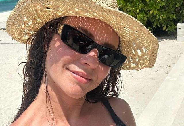 Paolla Oliveira tira selfie na praia usando óculos de sol e chapéu