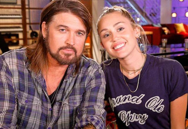 Miley Cyrus e Billy Ray Cyrus posam juntos olhando para a câmera