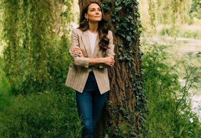 Kate Middleton posa no jardim com os braços cruzados e olhando para o horizonte
