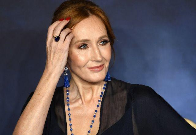 J.K Rowling posa olhando para o lado e com a mão na cabeça